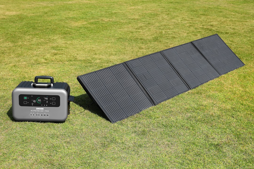 Solar panel connected to portable battery storage unit on grass, demonstrating solar energy storage technology
